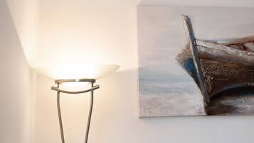 Um candeeiro com cúpula branca e um quadro de um barco na parede.
