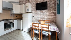 Una cucina con parete in mattoni, televisore e tavolo da pranzo con sedie.