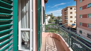 Un balcone con vista su una strada, un edificio con un cartello che riporta 'HOTEL RESTAURANTE' e un cielo azzurro intenso.