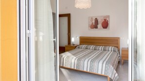 Un dormitorio con cama, mesitas de noche, una lámpara, una lámpara colgante y un cuadro en la pared.