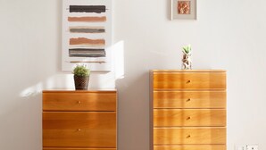 Una habitación con un aparador de madera, un cuadro abstracto colgado en la pared y una fotografía enmarcada.