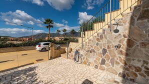 A stone staircase leading to a balcony with a view of palm trees and mountains.