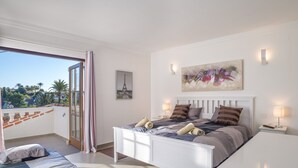 A bedroom with a bed, a bedside table, a nightstand, a painting, and a view of the Eiffel Tower. - Villa 'Scandinavian Design' with Sea View, Wi-Fi and Air Conditioning (Puerto Banús)