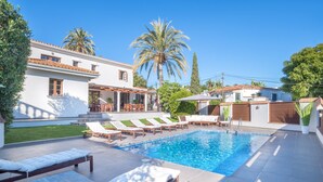 A swimming pool with lounge chairs, a patio area, and a white building with a tiled roof. - Villa 'Scandinavian Design' with Sea View, Wi-Fi and Air Conditioning (Puerto Banús)