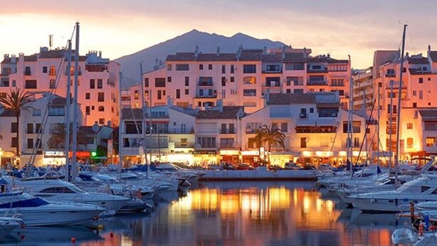 A marina with boats docked, buildings with balconies, and a mountain in the background. - Villa 'Scandinavian Design' with Sea View, Wi-Fi and Air Conditioning (Puerto Banús)