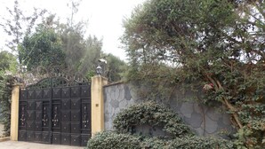 Una entrada cerrada con un muro de piedra y una reja de metal.