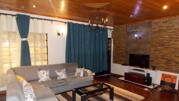 Una sala de estar con un sofá gris, una mesa de centro, un televisor y una pared de piedra.