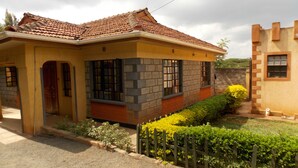 Una casa de dos pisos con techo de tejas, fachada de ladrillo y un pequeño jardín con cerca de madera.