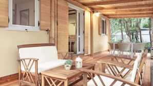 A wooden deck with a table and chairs, a sofa, and a small potted plant. - Mobilhome Deluxe by Interhome (Rovinj/Bale)