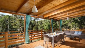 A covered outdoor area with wooden flooring, a table with chairs, a sofa, and lounge chairs. - Mobilhome Villa Prestige by Interhome (Rovinj/Bale)