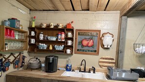 A rustic kitchen with wooden shelves, a coffee maker, and a sink. - Rustic and Romantic Farm House (Louisa)