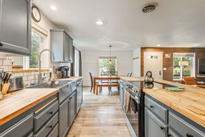 A modern kitchen with a central island, wooden countertops, and built-in appliances. - Walk to Downtown Sisters - DOG Friendly - Updated! (Sisters)