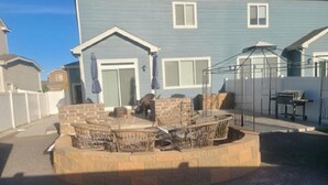 A backyard with a stone fire pit, outdoor furniture, and a covered seating area. - Cute & Cozy 3 BdRm, 2 1/2 Bath Townhome (Evans)