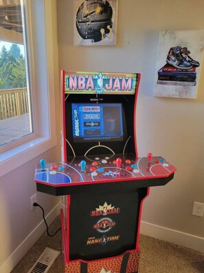 Una máquina de salón recreativa con el título "NBA JAM" y un panel de control con volante.