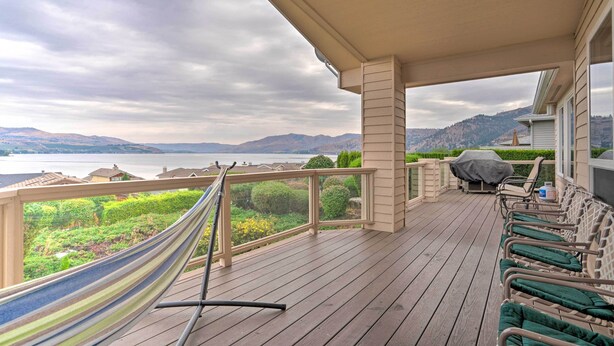 Un terrazzo in legno con un'amaca, mobili da esterno e vista su un lago e montagne.