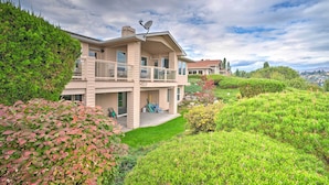 Una casa a due piani con un balcone, immersa nel verde e sotto un cielo sereno.