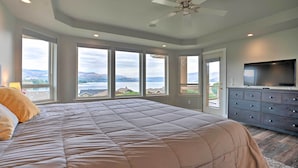Una camera da letto con un grande letto, un ventilatore a soffitto, una TV e vista sull'esterno.