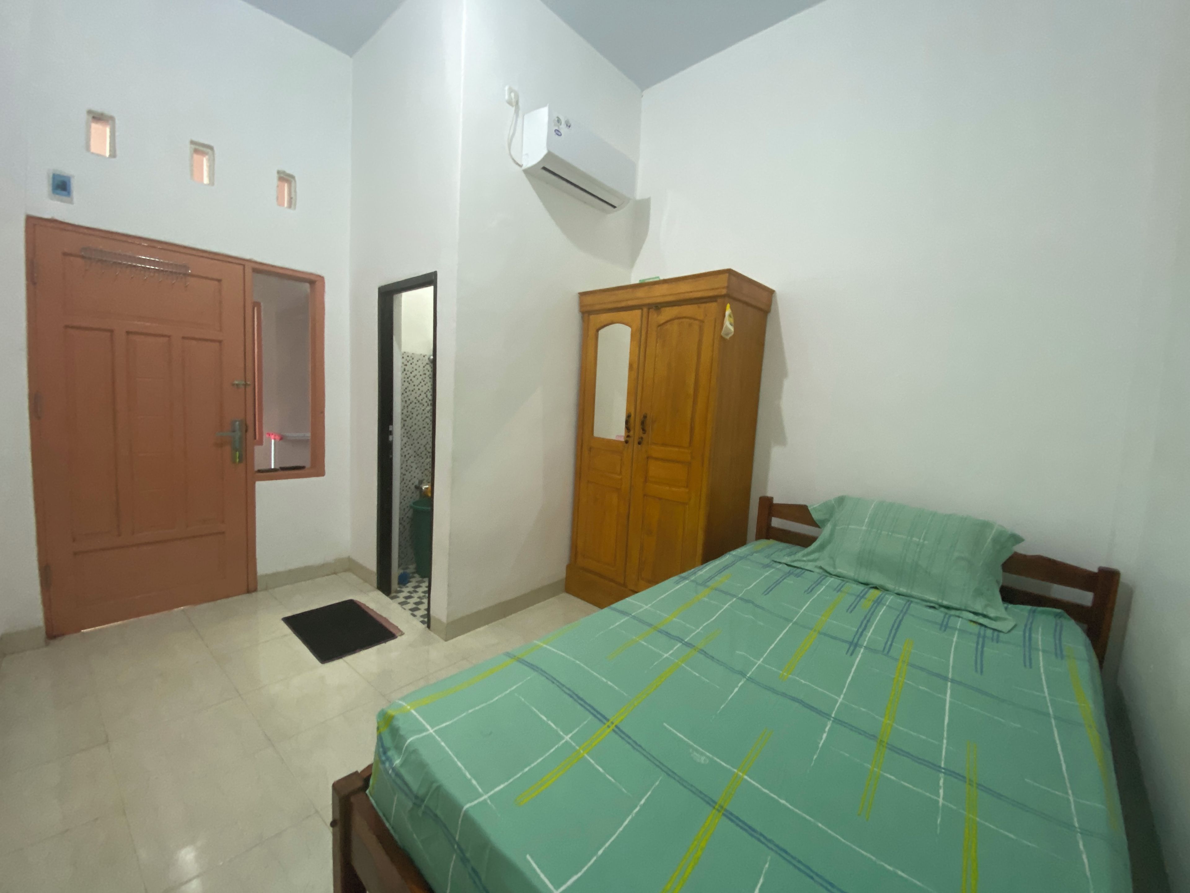 A bedroom with a bed, wardrobe, and a door.