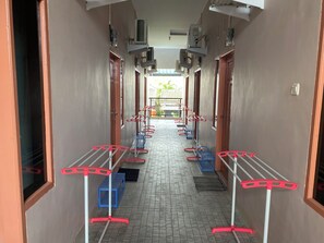 Un pasillo con unidades de aire acondicionado, puertas y tendederos.