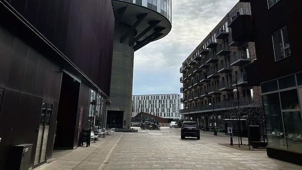 Een modern stadsgebouw met een gebogen glazen gevel en een plat dak.