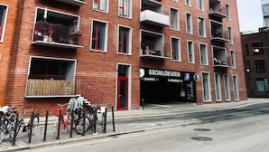 Een meerhoog gebouw van baksteen met balkons, een duidelijke ingang en een bordje met 'KRONLOBSØEN'.