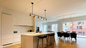 Een moderne keuken met een centraal kookeiland, barstoelen en hanglampen.