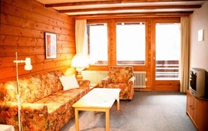Relax in this inviting room with a floral-patterned sofa, wooden table, and large window offering a view.