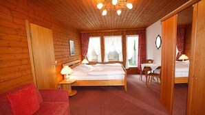 A wooden-paneled room with a bed, a red sofa, a desk, and a chair. - Fewo 3E Terr., Kochnische, 1 Schlaf- und 1 Wohn-/schlafzimmer, max 4 Pers (Ruhpolding)