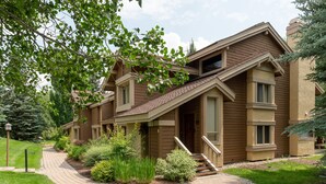 A two-story house with a sloped roof, a front porch, and a landscaped garden.