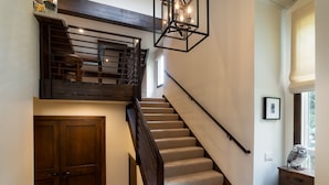 A staircase with a wooden railing and beige carpet, leading to a landing with a wooden door and a small table with a decorative owl.