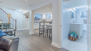 A spacious living area with a staircase, a dining area, and a kitchen with bar stools.