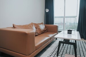 Una sala de estar moderna con un sofá de cuero marrón, una mesa de centro blanca y un tapete de diseño blanco y negro.