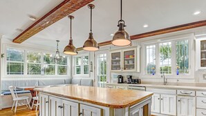 A spacious kitchen with a large island, white cabinetry, and a wooden ceiling. - North Beach Tybee Home With Roof Top Deck | Walk to Beach | Heated pool access (Tybee Island)