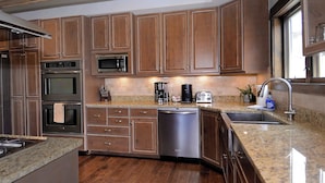 A kitchen with wooden cabinets, stainless steel appliances, granite countertops, and a dishwasher. - Whetstone Wonder, Views! Pet Friendly, Hot tub (Mt. Crested Butte)