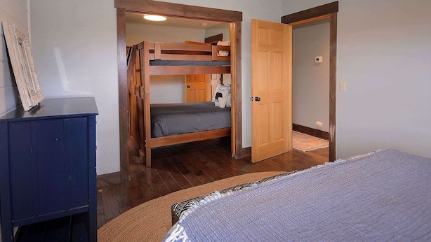A room with a bunk bed, a wardrobe, and a door leading to another room. - Whetstone Wonder, Views! Pet Friendly, Hot tub (Mt. Crested Butte)
