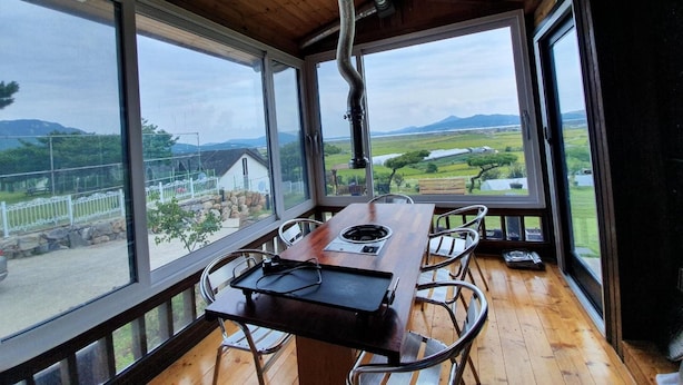 Un comedor con una mesa grande y sillas, ventanas amplias que ofrecen vistas al campo.
