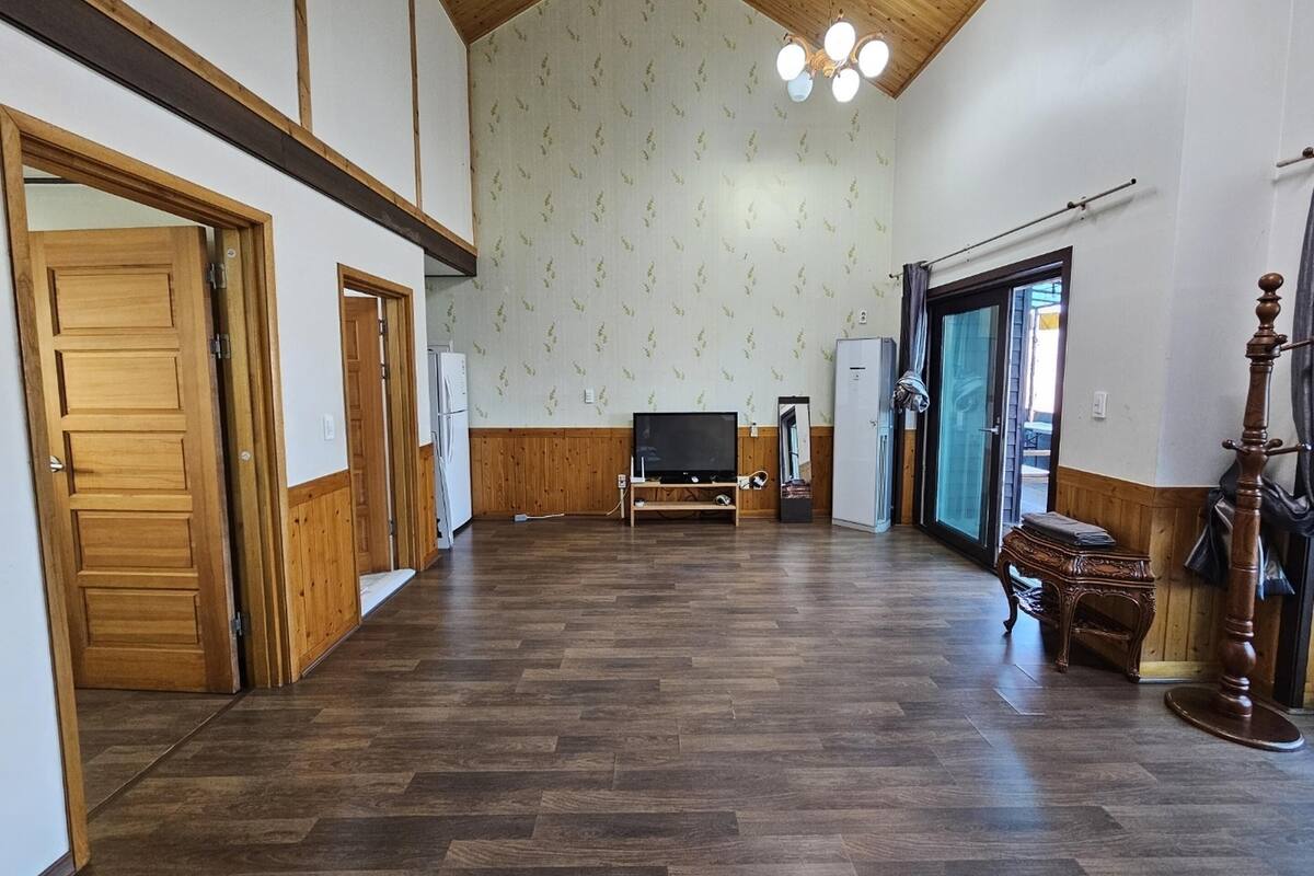 Une pièce spacieuse dotée d’un plancher en bois, d’une télévision, d’un réfrigérateur et d’une grande fenêtre.