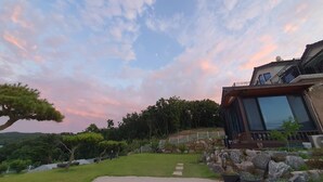Una casa moderna con un amplio ventanal, un camino de piedra y un jardín cuidado.