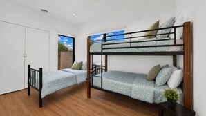 A bunk bed room with a wooden floor, white walls, and a view of the sky through a window. - Beach View Escape - Close to the Beach & WiFi (Safety Beach)