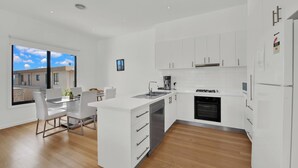 A modern kitchen with white cabinets, a built-in oven, and a coffee maker. - Beach View Escape - Close to the Beach & WiFi (Safety Beach)