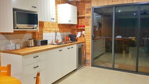 Eine moderne Küche mit weißen Schränken, einer Holz Arbeitsplatte, einer Mikrowelle, einem Wasserkocher und einem Geschirrspüler.