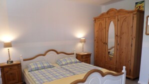 Camera da letto con un letto bianco, un armadio in legno e due comodini con lampade.
