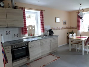 A kitchen with a stove, sink, and dining table with chairs.