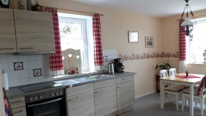 Una cucina con fornello, lavandino e tavolo da pranzo con sedie.
