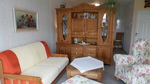 Un soggiorno con un divano, due poltrone, un mobile in legno e un quadro appeso al muro.