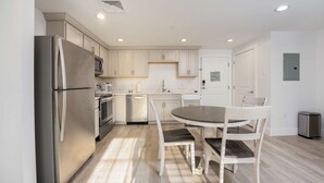 A modern kitchen with white cabinetry, stainless steel appliances, and a round dining table with chairs.