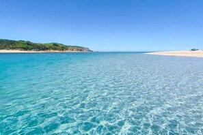 A beach with clear turquoise water and a sandy shore.