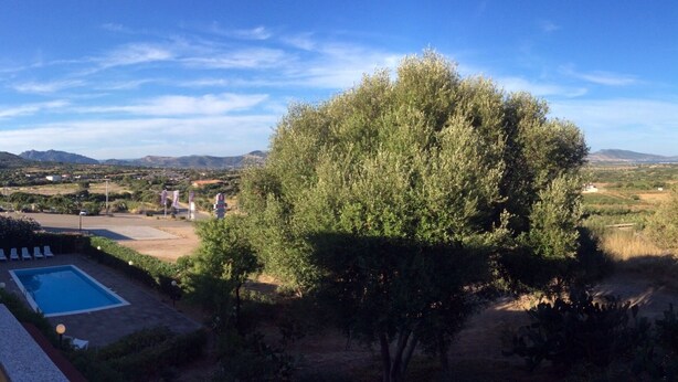 A pool area with a view of distant hills and trees. - Holiday Home Residence "i delfini" (Badesi)