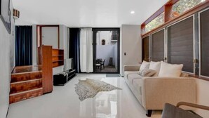 Una sala de estar moderna con un sofá, una mesita de centro, un tapete y una escalera que conduce a otra habitación.