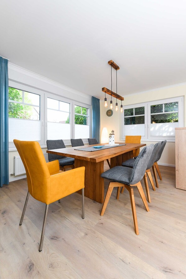 Un coin repas avec une table en bois, six chaises et un luminaire suspendu.